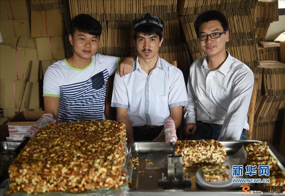 5月22日，阿迪力和蒋春杨一起将核桃仁倒入盛有糖稀的锅中。 新华社记者 李尕 摄