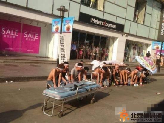 8月3日下午3点，湖北武汉中山大道佳丽广场，十多名赤膊男子披麻戴孝，用门板抬着一具“尸体”在此示威，宣称城管打死人。