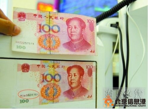  编号为Ｍ３Ｗ９６０５１５１的假币（下），正面和真币几乎完全一样，店家将它张贴在收银柜外，提醒自己不要再上当。
（记者 张哲 摄）