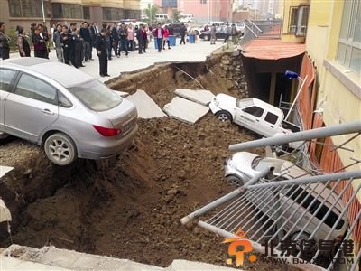 图为路面塌陷后车辆掉入深坑中的情景。